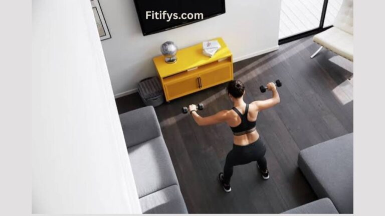 A woman in workout clothes exercising at home with dumbbells, standing in a living room near a yellow cabinet and TV, with the text “Fitifys.com” at the top.