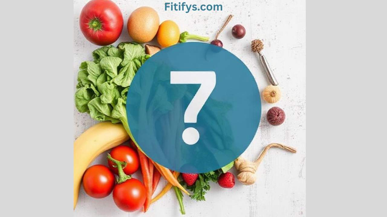 A flat lay arrangement of various fresh fruits and vegetables on a light surface, including tomatoes, lettuce, carrots, bananas, strawberries, garlic, onions, and citrus fruits. At the center is a large blue circle with a white question mark symbol, partially covering the produce. The text "Fitifys.com" is displayed at the top in blue.
